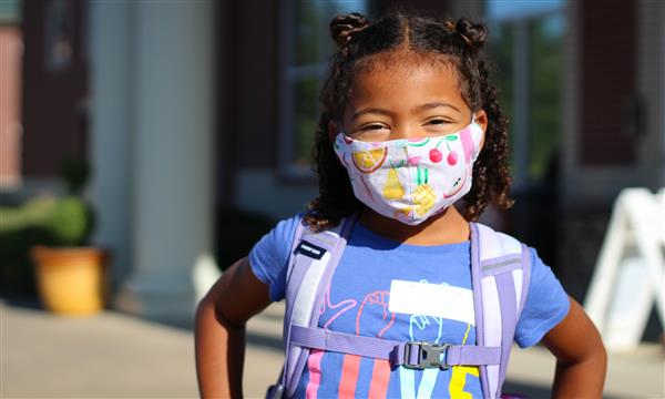 girl smiles while wearing mask